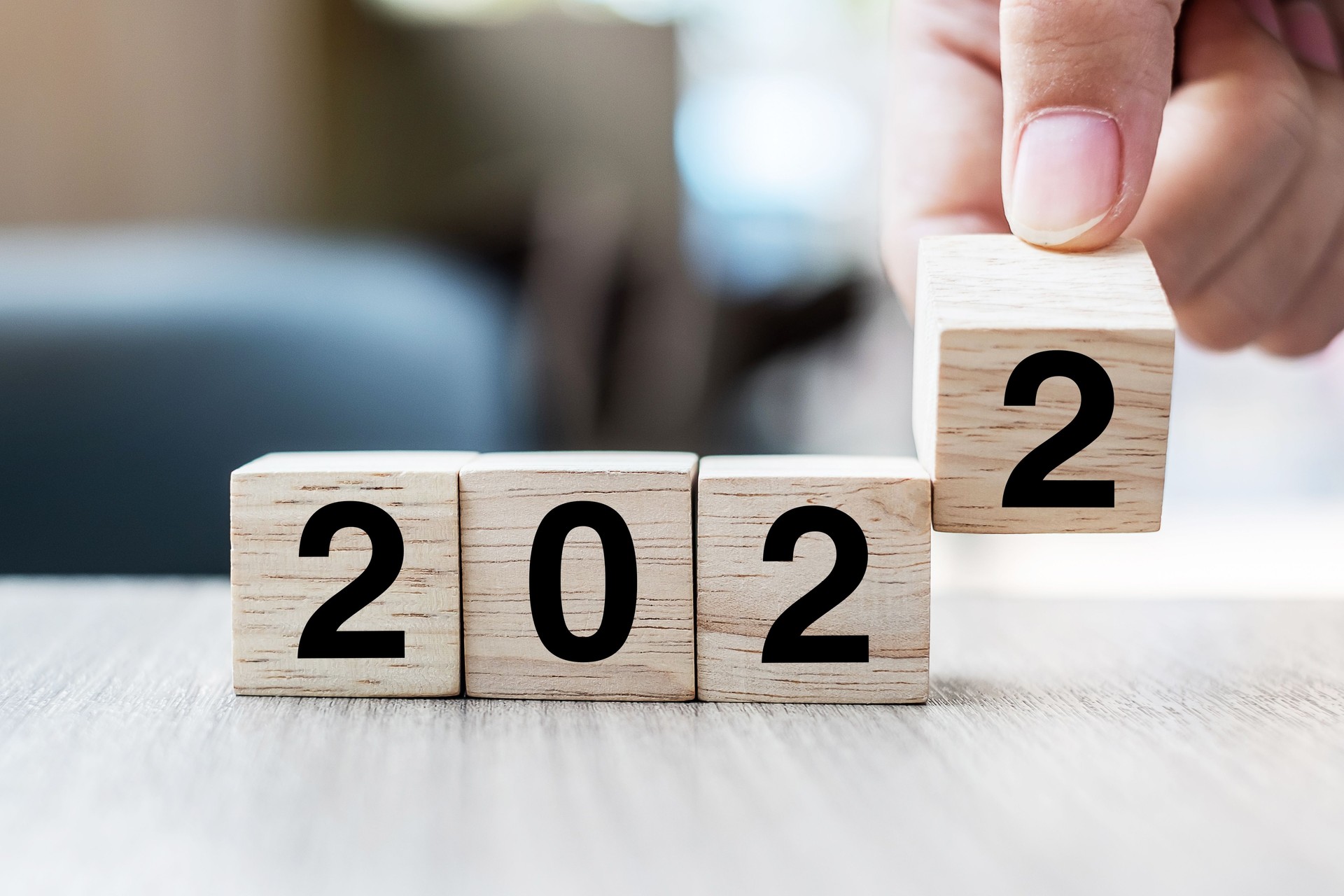 Businessman hand holding wooden cube with flip over block 2021 to 2022 text on table background. Resolution, strategy, solution, goal, business and New Year holiday concepts
